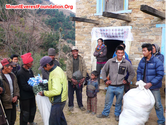 everyone watches while Gyel Chiri Sherpa hands out a blanket to one of the poorest people in the village, a deaf, mute, and mentally challenged person.